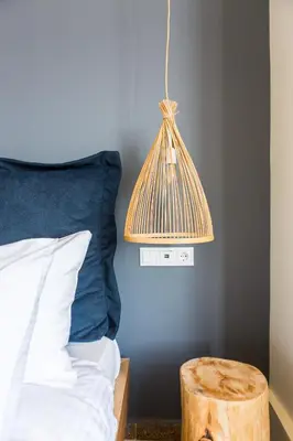 a lamp hanging over a bed with a blue wall at Ciel Living Athens in Athens