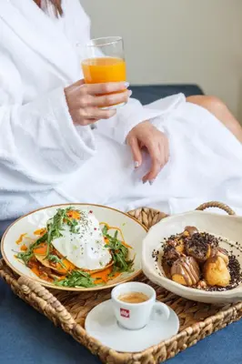 a person holding a glass of orange juice and a plate of food at Ciel Living Athens in Athens
