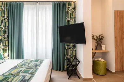 a bedroom with a tv on a wall with a bed at Garment District Suites in Athens