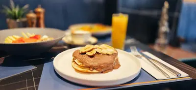 a white plate with a sandwich with waffles and fruit at Garment District Suites in Athens