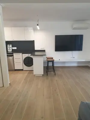 a room with a kitchen with a tv on the wall at Newly Renovated Varkiza Beachside One Bedroom with Large Terrace in Athens