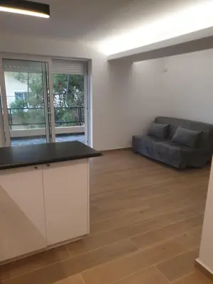 an empty living room with a couch and a kitchen at Newly Renovated Varkiza Beachside One Bedroom with Large Terrace in Athens