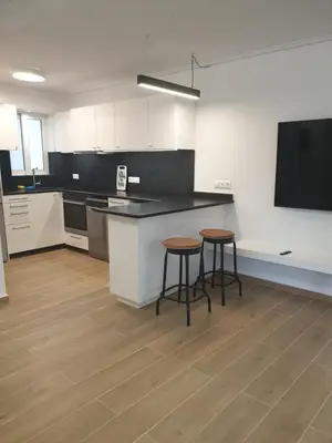 a kitchen with two stools and a counter and a tv at Newly Renovated Varkiza Beachside One Bedroom with Large Terrace in Athens