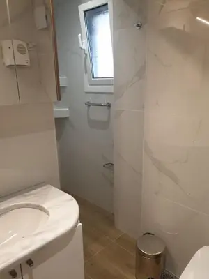 a white bathroom with a toilet and a sink at Newly Renovated Varkiza Beachside One Bedroom with Large Terrace in Athens