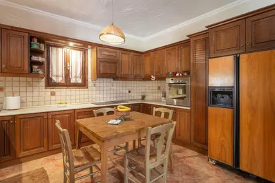 a kitchen with wooden cabinets and a wooden table with chairs at Maria's Home in Dhaskalión