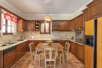a kitchen with wooden cabinets and a wooden table with chairs at Maria's Home in Dhaskalión