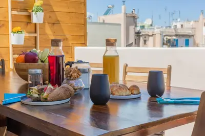 a table with plates of food and a bottle of juice at 100m2 Luxury Apartment in the Heart of Athens - Living Stone Emerald in Athens