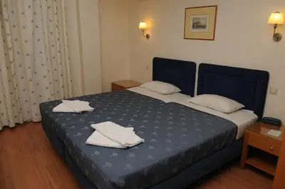 a bedroom with a blue bed with white towels on it at Hotel Pantheon in Markopoulo