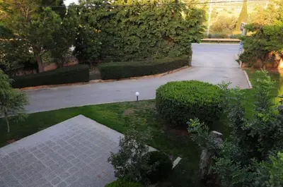 an empty driveway in a garden with bushes and trees at Hotel Pantheon in Markopoulo