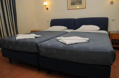 a blue bed with two pillows on top of it at Hotel Pantheon in Markopoulo