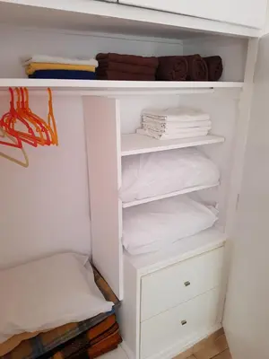 a white closet with white shelves and towels at Filopappou Hill Apartment in Athens