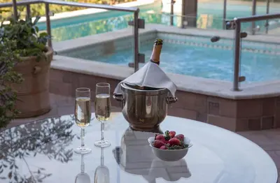 a bottle of wine and glasses on a table with a bowl of fruit at Exceptional Villa in Voula near the sea in Athens