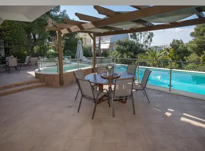 a patio with a table and chairs next to a pool at Exceptional Villa in Voula near the sea in Athens