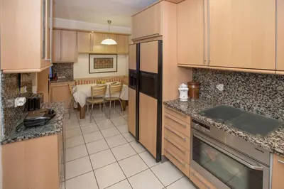 a kitchen with wooden cabinets and a table in the background at Exceptional Villa in Voula near the sea in Athens