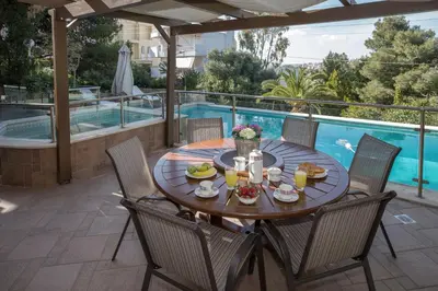 a table with food and drinks on a patio with a pool at Exceptional Villa in Voula near the sea in Athens