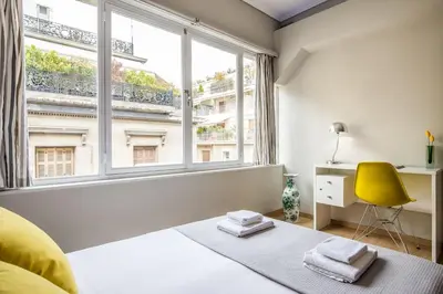 a white bedroom with a yellow chair and a large window at Stay like a local next to Acropolis & Plaka! in Athens