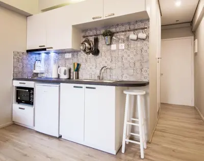 a kitchen with white cabinets and a bar stool at Treat yourself w. this central City-break studio! in Athens