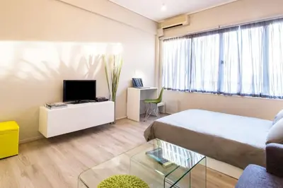 a bedroom with a bed and a tv and a couch at Treat yourself w. this central City-break studio! in Athens