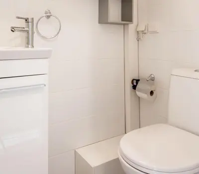 a white bathroom with a toilet and a sink at Treat yourself w. this central City-break studio! in Athens