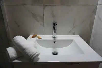 a white bathroom sink with towels and a faucet at Afrodite's apartment (close to Athens city center) in Athens