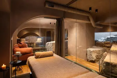 a bedroom with a large bed in a room with a stone wall at Niche Hotel Athens in Athens