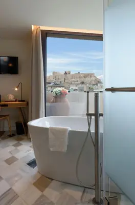 a bath tub in a bathroom with a view ofhens at Niche Hotel Athens in Athens