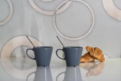 two coffee cups and a croissant on a table at Acropolis Junior Suite in Athens