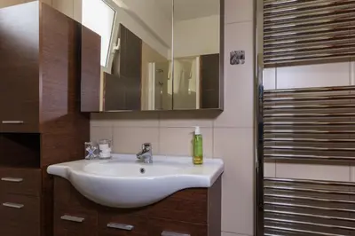 a bathroom with a white sink and a mirror at Alexander Apartments Airport in Spáta