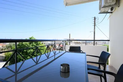 a balcony with a table and chairs and a view at Alexander Apartments Airport in Spáta