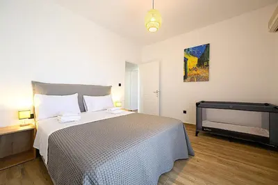 a bedroom with a bed and a painting on the wall at Alexander Apartments Airport in Spáta