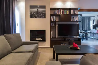 a living room with a couch and a tv at Alexander Apartments Airport in Spáta