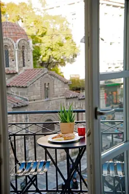 a table and chair on a balcony with a window at Four Streets Athens - Luxury Suites Apartments in Athens in Athens