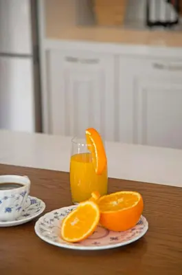 a glass of orange juice and orange slices on a table at Four Streets Athens - Luxury Suites Apartments in Athens in Athens