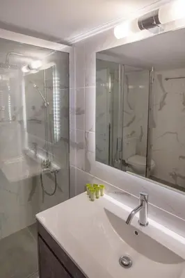 a bathroom with a sink and a large mirror at Roomy and comfortable apartment near Acropolis by GHH in Athens