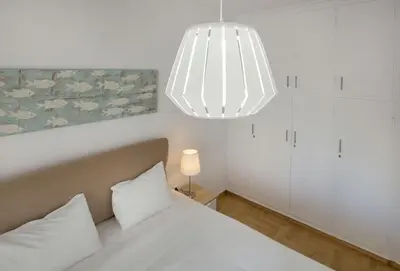 a bedroom with a white bed and a chandelier at Roomy and comfortable apartment near Acropolis by GHH in Athens