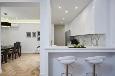 a kitchen and dining room with white cabinets and bar stools at Luxurious Spacious Apt next to Hilton Hotel in Athens