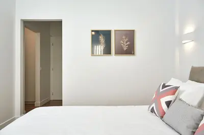 a bedroom with a white bed with two pictures on the wall at Luxurious Spacious Apt next to Hilton Hotel in Athens