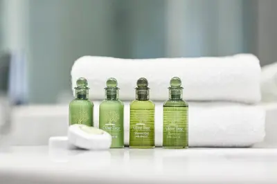 four bottles of green liquid on a counter with towels at Modern Elegant Apt at Kolonaki in Athens