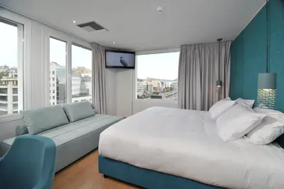a bedroom with a bed and a couch and windows at Athenaeum Smart Hotel in Athens