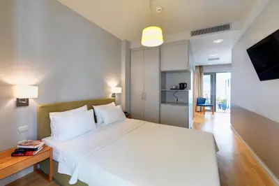 a bedroom with a large white bed and a television at Phidias Piraeus Hotel in Piraeus