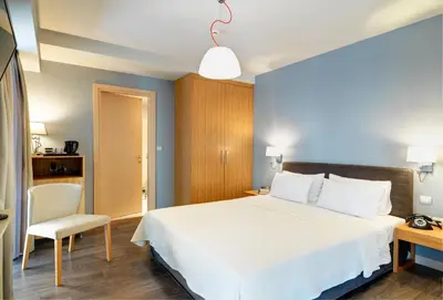 a bedroom with a white bed and a chair at Phidias Piraeus Hotel in Piraeus