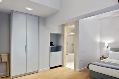 a bedroom with white walls and a bed and a closet at Phidias Piraeus Hotel in Piraeus