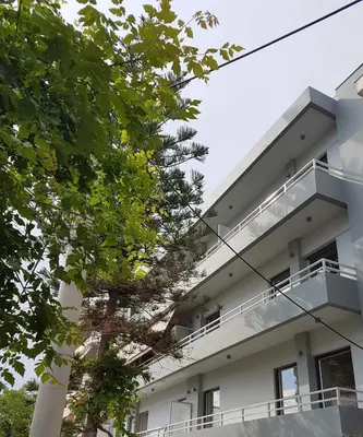 a white building with trees in front of it at AT.thea ATHENS BOUTIQUE APARTMENTS in Athens