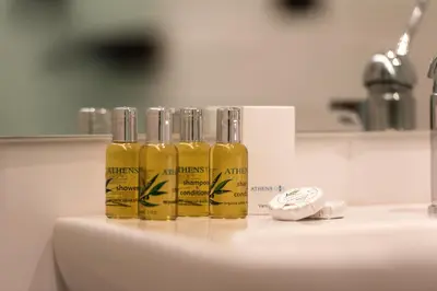 three bottles of oil sitting on top of a sink at Athens One Smart Hotel in Athens