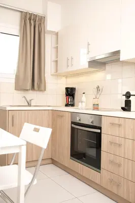 a kitchen with white appliances and a white table and chair at Metro Fix Cosy Apartment in Athens