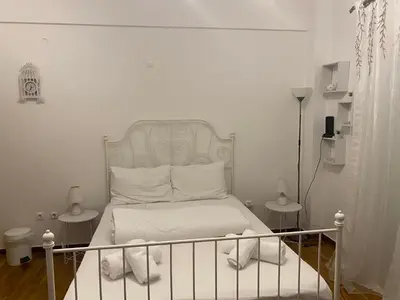 a white bedroom with a bed with a metal headboard at Modern, ideally located studio apartment in Athens