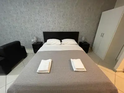 a large bed with two towels on top of it at AVR Airport Deluxe Suites 4 AIRPORT FREE SHUTLE in Markopoulo