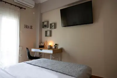 a bedroom with a bed and a desk with a television on the wall at COZY APT NEXT TO METRO AND CLOSE TO ACROPOLIS! in Athens