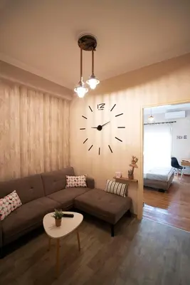 a living room with a couch and a clock on the wall at COZY APT NEXT TO METRO AND CLOSE TO ACROPOLIS! in Athens