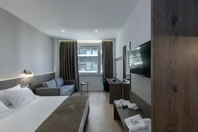 a hotel room with a bed and a couch and a television at Philosofia Athens Suites in Athens